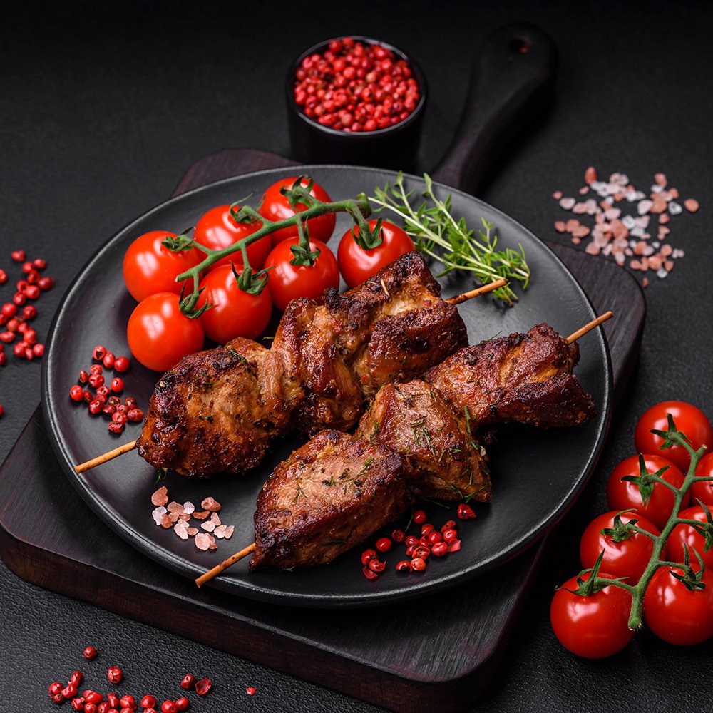 Delicious grilled chicken, turkey or pork skewers with salt, spices and herbs on a fire on a dark concrete background