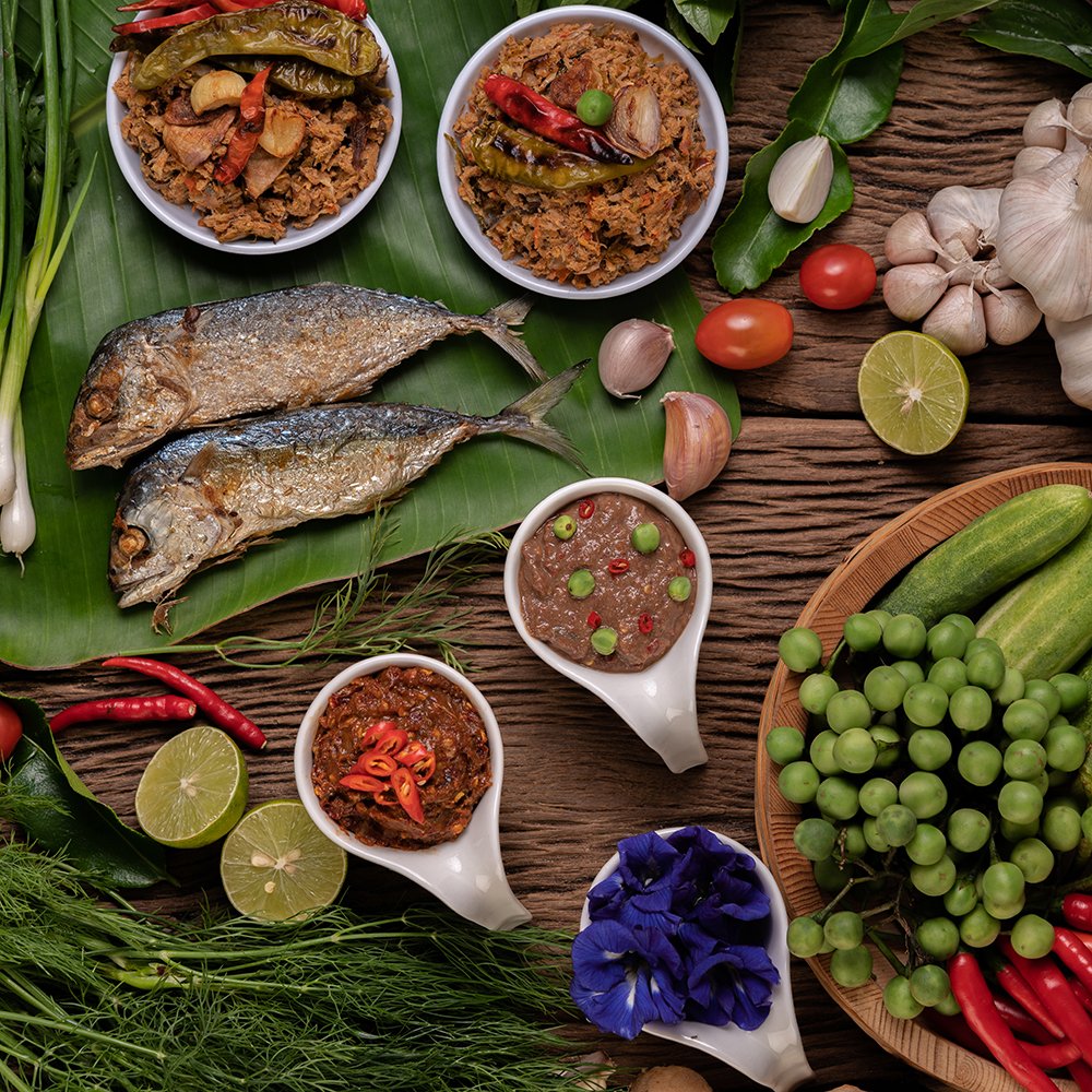 Shrimp paste, mackerel, fried on banana leaves, chili, tomato, garlic and lemon on wooden floor.